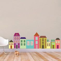 a room with a white chair and some colorful houses on the wall next to it