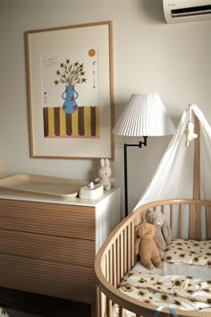 a baby crib with a teddy bear in it and a lamp next to it