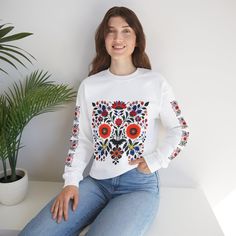 Hungarian Kalocsa Motif design on a cozy Unisex Heavy Blend Crewneck Sweatshirt, giving off a warm and cultural vibe. Perfect for those who appreciate traditional Hungarian embroidery and enjoy staying warm in style. Ideal for winter holidays and cultural celebrations. Product features - Knit in one piece without side seams for reduced fabric waste - Ribbed knit collar with seam for elasticity and shape retention - Medium-heavy fabric blend of 50% cotton and 50% polyester for coziness in colder months - Classic fit with crew neckline for comfort and style - Ethically made with US grown cotton and sustainable production practices Care instructions - Machine wash: cold (max 30C or 90F) - Non-chlorine: bleach as needed - Tumble dry: low heat - Do not iron - Do not dryclean Folk Style Long Sleeve Embroidered Top With Motif, Embroidered Long Sleeve Folk Shirt, Hungarian Embroidery, Sweat Top, Cultural Celebration, Motif Design, Festival Fashion, Ribbed Knit, Jumper