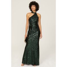 a woman wearing a green sequin gown with a halter top and long skirt