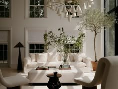 a living room filled with furniture and a chandelier hanging over the top of it