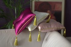 two pillows with tassels are sitting on a couch