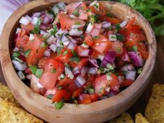 a wooden bowl filled with salsa next to tortilla chips