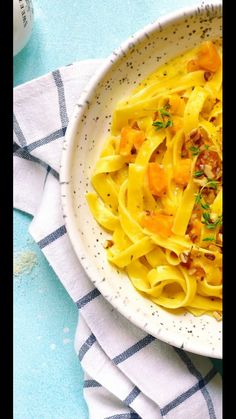 a white bowl filled with pasta on top of a blue table