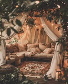 a living room filled with lots of pillows and furniture under a canopy covered in lights