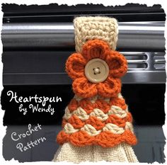 an orange and white crochet flower sits on top of a oven mitt