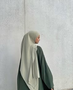 a woman wearing a green and white shawl is standing in front of a wall