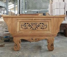 a wooden bench with carvings on it in a room filled with chairs and other furniture