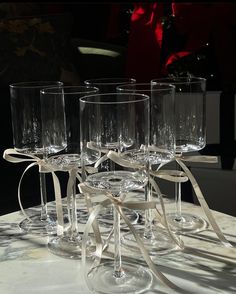 four wine glasses with bows on them sitting on a table