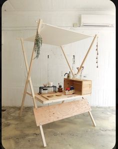 a wooden table with a white canopy over it and other items on the top shelf