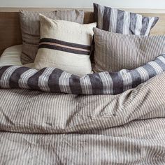 an unmade bed with striped sheets and pillows