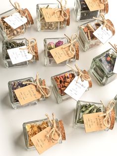 several small glass containers filled with different types of spices and tea bags tied with twine