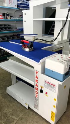 a machine that is sitting on top of a blue table in a room filled with shelves