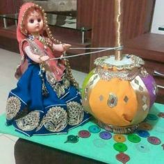 a doll sitting on top of a table next to a pumpkin