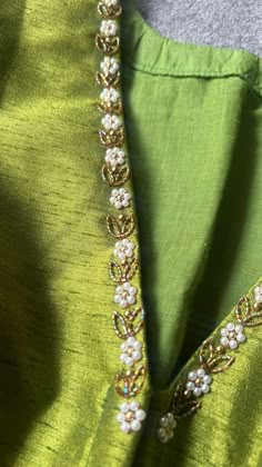 the back of a green dress with pearls on it