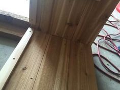 a wooden bench sitting on top of a floor next to a power cord and wires