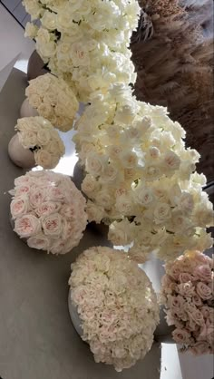 white and pink flowers are arranged in vases on a table with an oval mirror behind them