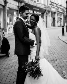 a bride and groom standing together on the street