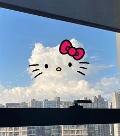 a window with a hello kitty sticker on it's side in front of a cityscape