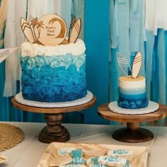 two cakes with blue and white frosting sitting on top of wooden stands next to each other