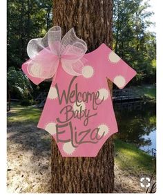 a pink welcome baby sign hanging on a tree