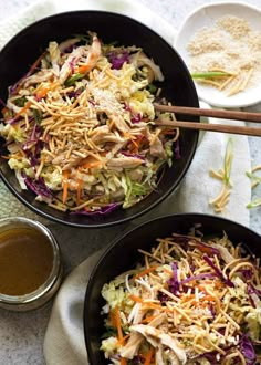 two black bowls filled with coleslaw and carrots on top of a table