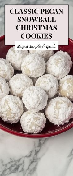 a red bowl filled with snowball cookies on top of a marble countertop next to a white sign that says classic pecan snowball christmas cookies