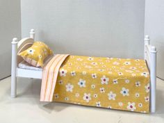 a small doll bed with yellow and white flowers on it