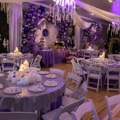 a room filled with lots of tables covered in purple and white decorations