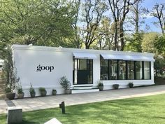 a white building with the word goop written on it's side in front of some trees