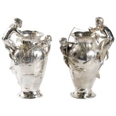 two silver vases sitting next to each other