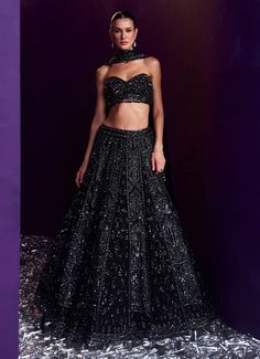 Elevate your style with the exquisite Black Sequins Embroidered Bridal Lehenga Set, a true masterpiece of craftsmanship and design. Crafted from soft net, the black lehenga is beautifully adorned with intricate embroidery featuring tonal and gunmetal sequins, glass pipes, and shimmering crystals, creating a mesmerizing interplay of light and texture. Teamed with a stylish tube-cut blouse, this set adds a contemporary twist to the traditional silhouette, offering a flattering and modern fit. The ensemble is completed with a matching embellished dupatta that exudes sophistication, making it a perfect choice for brides or brides-to-be looking to make a statement at cocktail parties, ensuring you stand out with grace and style on your special day. Composition : Lehenga, Blouse and Dupatta - Ne Tube Blouse Lehenga, Black Colour Lehenga, Black Choli With Resham Embroidery For Navratri, Cocktail Lehenga, Traditional Black Sets With Sequins, Black Bridal Lehenga, Black Sets With Intricate Embroidery For Receptions, Black Fitted Sharara For Evening, Black Anarkali Set For Evening Festivals