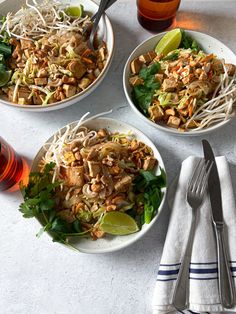 three white bowls filled with food on top of a table next to utensils