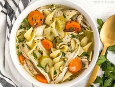 a bowl of chicken noodle soup with carrots, celery and parsley