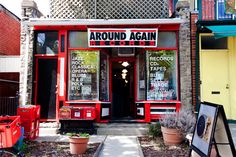 a red storefront with signs on the front and side windows that read around again