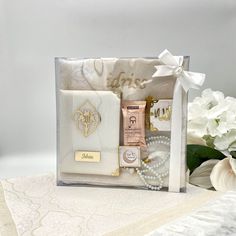 a white box with some items in it on top of a table next to flowers