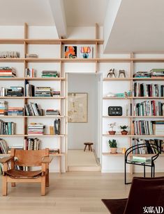 a living room filled with lots of furniture and bookshelves on top of wooden shelves