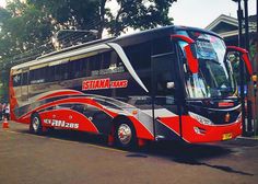 a red and black bus is parked on the street