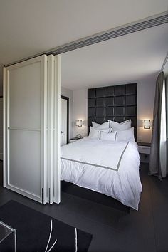 a large white bed sitting in a bedroom next to a tall black and white headboard