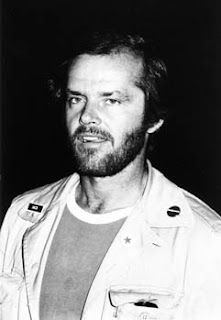 a black and white photo of a man with a beard in a jacket looking off to the side