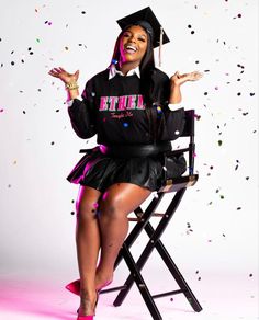 a woman sitting in a chair with confetti on her feet and wearing a graduation cap