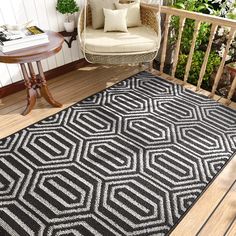 an outdoor area rug with a chair and table on the porch next to it,