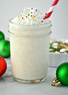 a glass filled with whipped cream surrounded by christmas ornaments