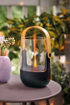 a glass vase sitting on top of a table next to a purple vase filled with flowers