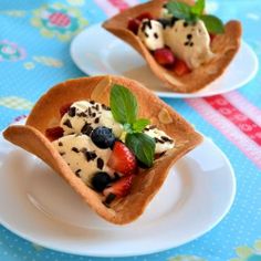 two dessert cups filled with fruit and ice cream on top of a blue table cloth