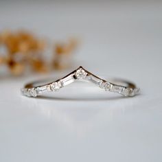 a diamond ring sitting on top of a white table next to some dried flowers in the background