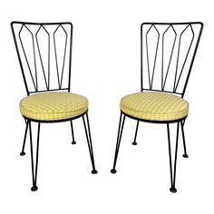 a pair of black metal chairs with yellow upholstered cushions