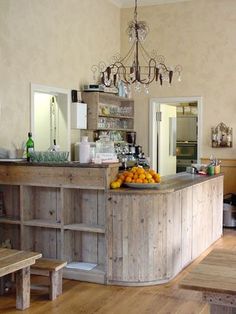 a wooden counter sitting in the middle of a room next to a table with oranges on it