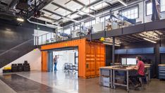 the inside of an industrial building with workers working on their desks and stairs in front of them