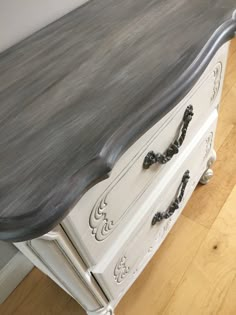 an old dresser painted white and grey with black handles